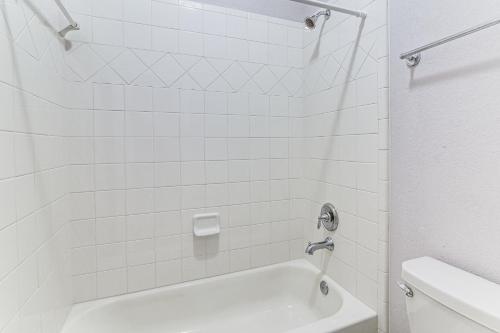 a white bathroom with a tub and a toilet at Grand Family Home with Patio and Fenced Yard in Arcola 
