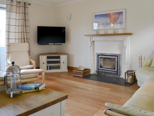 a living room with a fireplace and a tv at Middle Wicket in Trusham