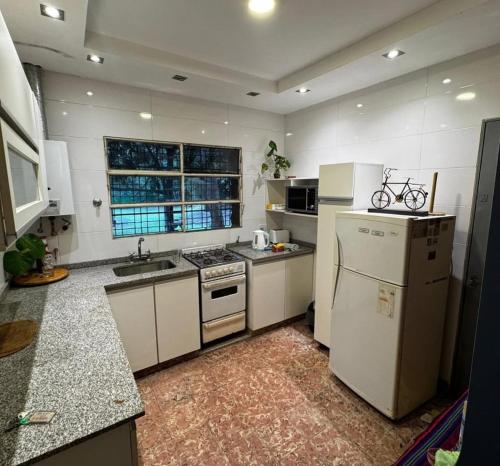a kitchen with white appliances and a sink and a refrigerator at La Manquel - Casa y Yungas in Yerba Buena