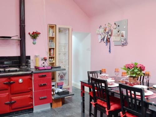 a dining room with a table and red cabinets at Sea Yonder in Buckie