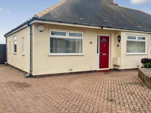 a house with a red door on a brick driveway at The Bay Cottage in Thornton