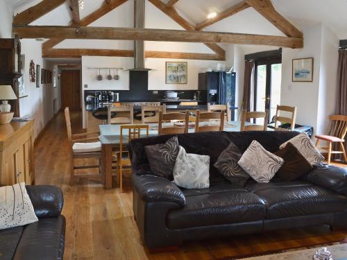 a living room with a leather couch and a kitchen at Glanrafon Isaf in Llanwnda