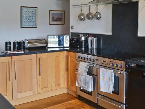 a kitchen with wooden cabinets and a stove top oven at Glanrafon Isaf in Llanwnda