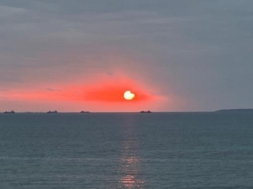 a sunset over the ocean with ships in the distance at Sunrise terrace kintown in Kin