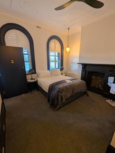 a bedroom with a bed with a fireplace and two windows at The Royal Hotel Bungendore in Bungendore
