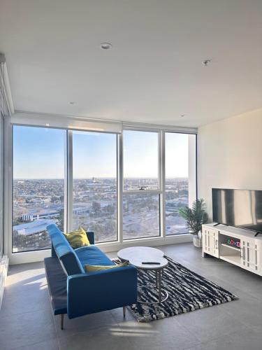 a living room with a blue couch and large windows at Luxurious city view at Sydney Olympic Park in Sydney