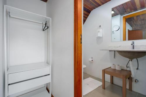 a bathroom with a sink and a mirror at Casa Sonnendorf 4 dorm Centro by Achei Gramado in Gramado