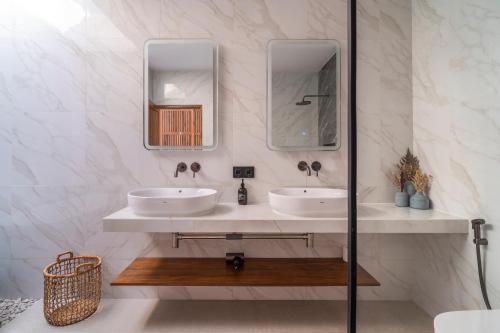 a bathroom with two sinks and two mirrors at Jago Gili Air in Gili Islands
