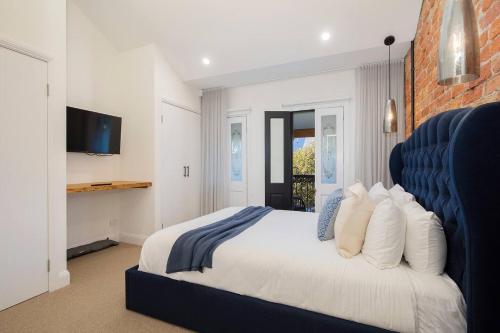 a bedroom with a large bed with a blue headboard at Casa Dianna - Timeless Terrace near CBD and Waterfront in Newcastle