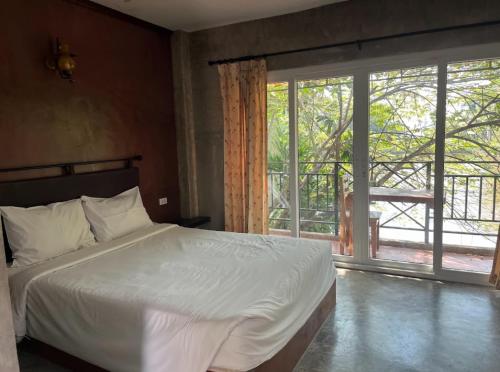 a bedroom with a bed and a large window at Blue Palm Resort in Bang Sare