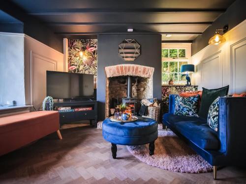 Una sala de estar con un sofá azul y un televisor. en Snowdrop Cottage, en Bulmer