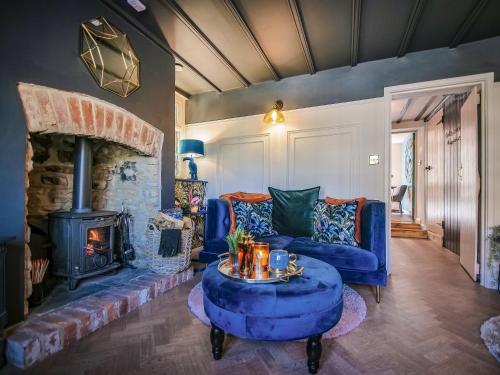 a living room with a blue couch and a fireplace at Snowdrop Cottage in Bulmer