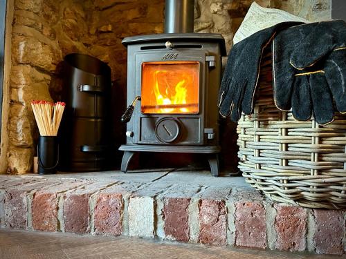 a wood burning stove in a brick fireplace at Snowdrop Cottage in Bulmer