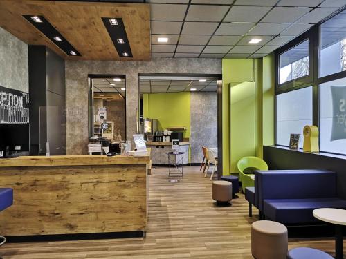 un hall de bureau avec un comptoir de réception et des chaises bleues dans l'établissement ibis budget Tours Centre Gare et congrès, à Tours