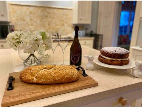a counter with a cutting board with a cake and a bottle of wine at Spacious 3-Bed Manor & Jacuzzi & BBQ Cabin in Maybole