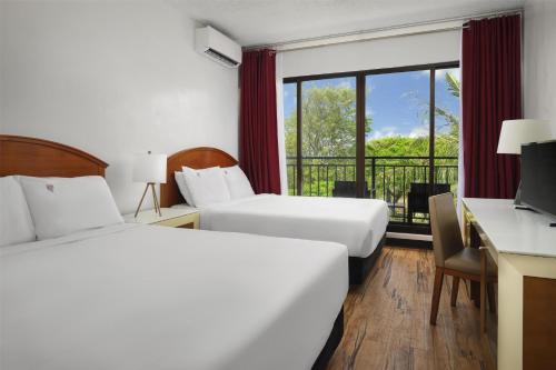 a hotel room with two beds and a balcony at SureStay by Best Western Guam Airport in Tamuning