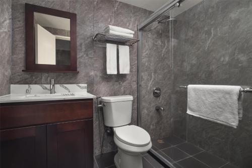a bathroom with a toilet and a sink and a shower at SureStay by Best Western Guam Airport in Tamuning