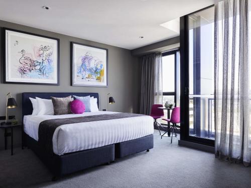 une chambre avec un grand lit avec des oreillers roses dans l'établissement Art Series - The Chen, à Box Hill