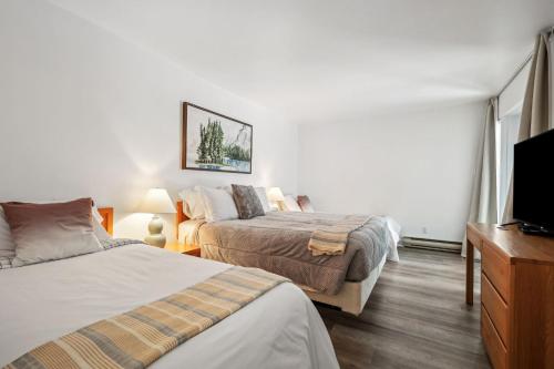 a bedroom with two beds and a flat screen tv at Big Sunshine in Mont-Tremblant