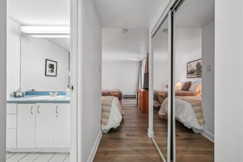 a room with two beds and a sink and a mirror at Big Sunshine in Mont-Tremblant