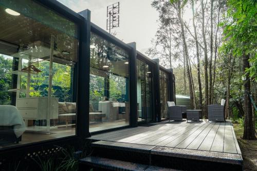 a house with glass walls and a wooden deck at Coastal Bliss New Brighton Eco Pod 50m to Beach in New Brighton