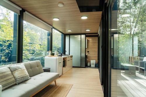 a living room with a couch and large windows at Coastal Bliss New Brighton Eco Pod 50m to Beach in New Brighton