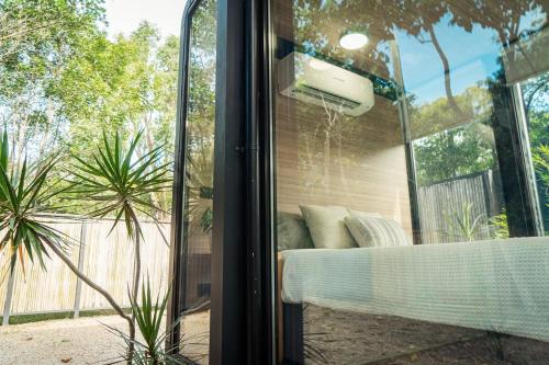 a glass door with a couch in a garden at Coastal Bliss New Brighton Eco Pod 50m to Beach in New Brighton