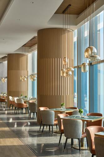 a restaurant with tables and chairs and large windows at MaxX by Steigenberger Harbour-view Qingdao in Qingdao