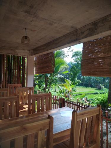 a dining room with a table and chairs and a field at Ananda Bungalow Tetebatu in Tetebatu