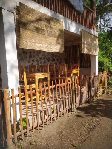 a fence in front of a house with a table and chairs at Ananda Bungalow Tetebatu in Tetebatu
