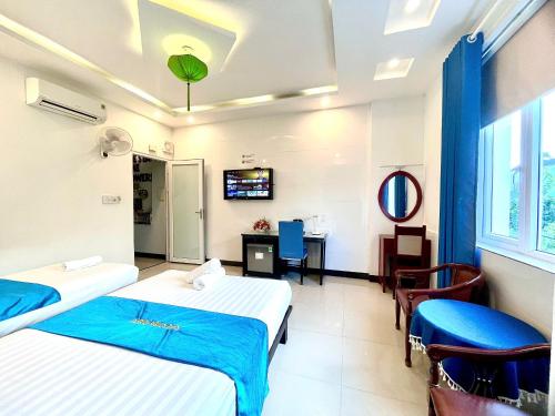 a hotel room with two beds and a tv at Flame Flowers Homestay in Hoi An