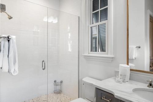 a white bathroom with a shower and a sink at Rosemary Bluegrass in Rosemary Beach