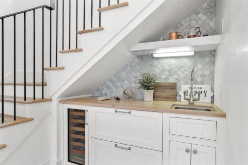 a white kitchen with a sink and a staircase at Rosemary Bluegrass in Rosemary Beach