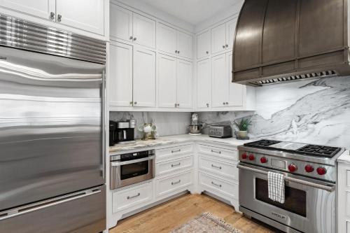 a kitchen with white cabinets and stainless steel appliances at Rosemary Bluegrass in Rosemary Beach
