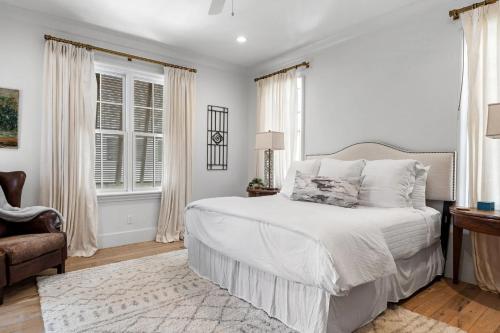 a white bedroom with a bed and a chair at Rosemary Bluegrass in Rosemary Beach