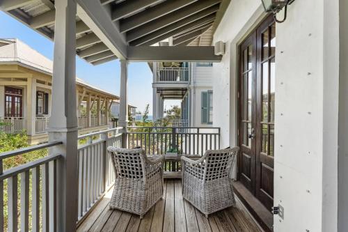 a porch with two wicker chairs on a wooden deck at Rosemary Bluegrass in Rosemary Beach