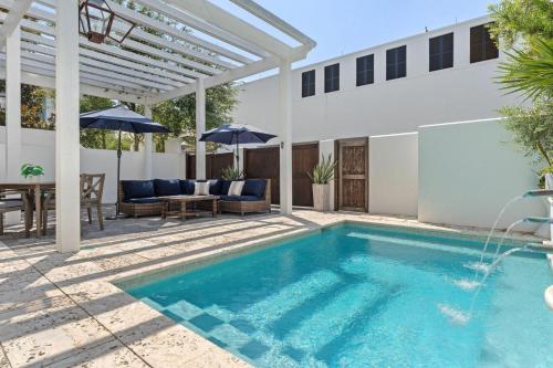 a swimming pool with a pergola and a house at Rosemary Bluegrass in Rosemary Beach