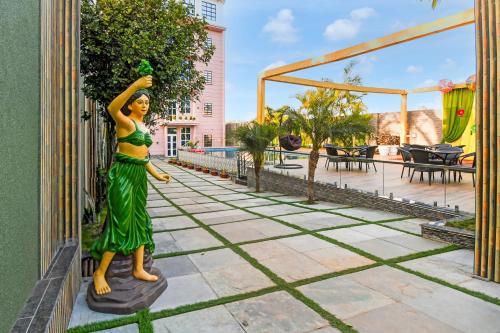 a statue of a woman in a green dress leaning against a wall at Hotel O M H Club And Resorts in Rānchī