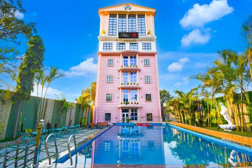 a pink building with a clock tower next to a swimming pool at Hotel O M H Club And Resorts in Rānchī