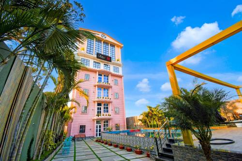 a pink building with palm trees in front of it at Hotel O M H Club And Resorts in Rānchī