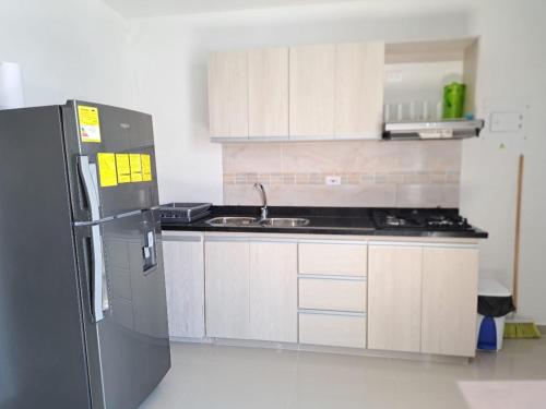 a kitchen with a black refrigerator and white cabinets at Vacaciones Inolvidables in Coveñas