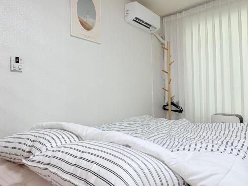 a white bed in a bedroom with a fan at Station House Daechi in Seoul