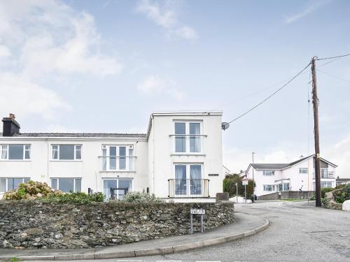 a white house with a stone wall at Seashell Cove in Cemaes Bay