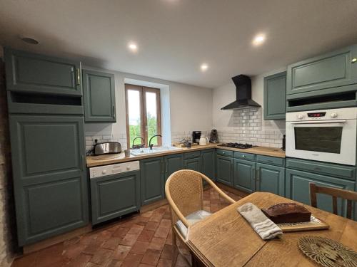 une cuisine avec des placards verts et une table en bois dans l'établissement Gîte Les Hirondelles à Chavroches - 5 personnes, animaux acceptés - FR-1-489-574, à Chavroches
