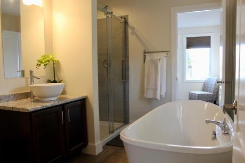 ein Badezimmer mit Badewanne, Waschbecken und Dusche in der Unterkunft Whitecaps Retreat Beach House 