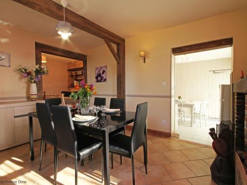 a dining room with a black table and chairs at Maison de charme avec grand jardin, proche Haras du Pin, animaux acceptés, idéale pour familles - FR-1-497-5 in Saint-Pierre-la-Rivière