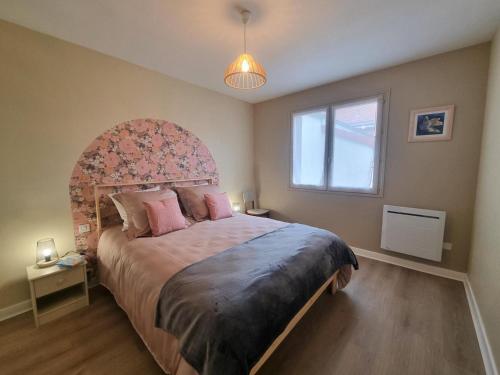 una camera con un grande letto con testiera decorata di Gîte spacieux avec terrasse, cheminée, wifi et parking à Roanne - FR-1-496-337 a Roanne