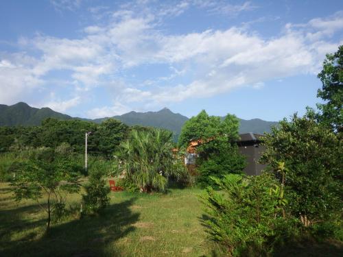 a field with trees and mountains in the background at Green Cottage ＭＭ in Yakushima