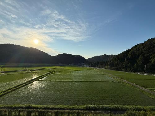 a field of grass with the sun in the background at Auberge eaufeu in Komatsu