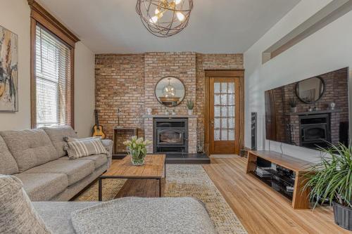 a living room with a couch and a brick wall at Le Manoir des Braves - Piscine in Quebec City